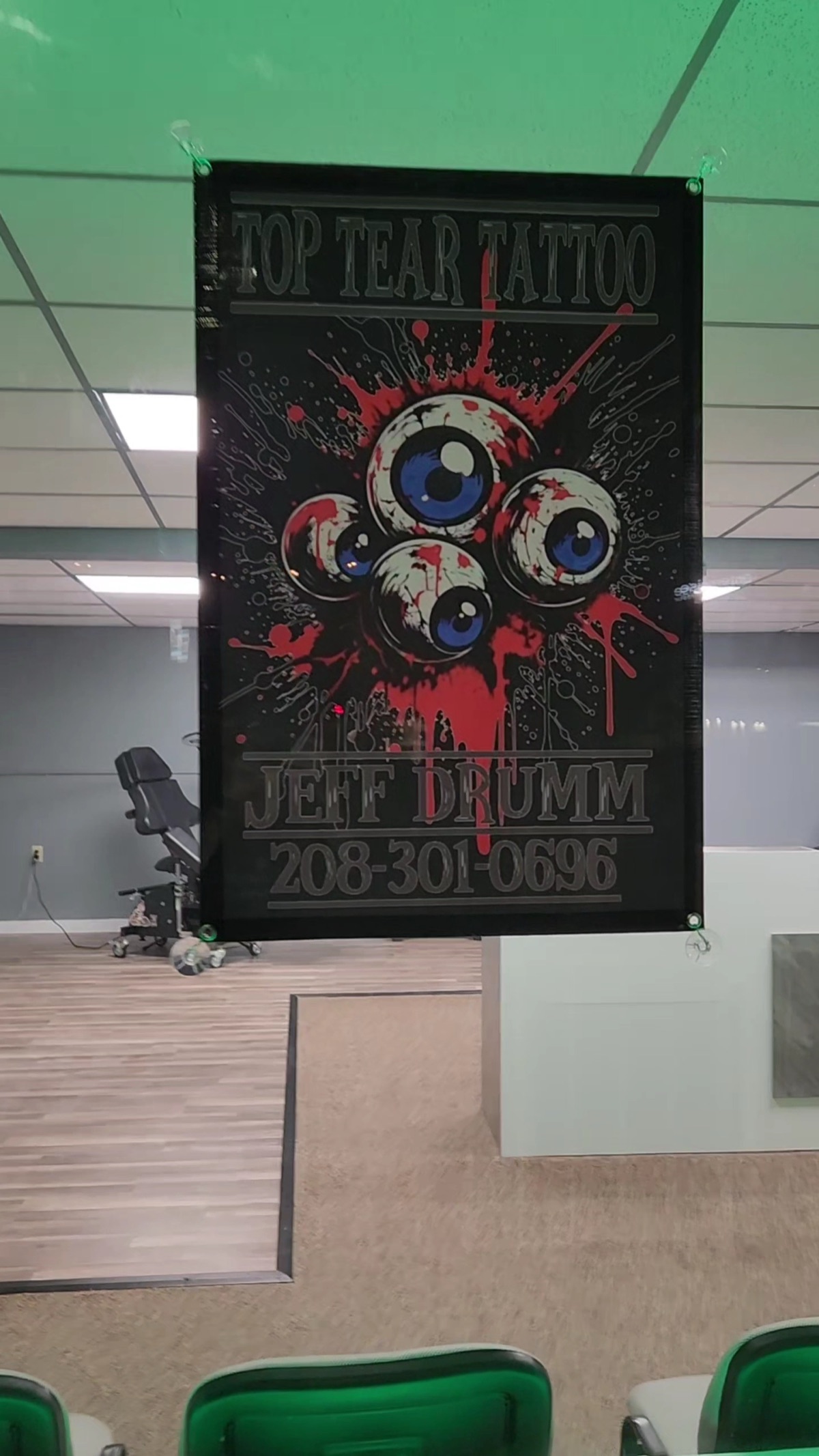 The Top Tear Tattoo banner in the shop, red eyeballs and the name Jeff Drumm.